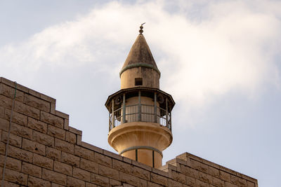 Low angle view of bell tower amidst buildings against sky minaret 