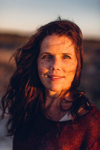 Portrait of beautiful young woman standing against sky during sunset