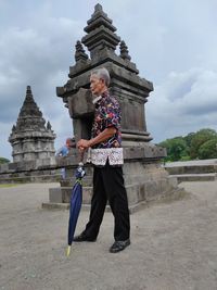 Full length of man with umbrella standing by built structure