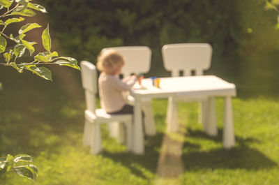 Rear view of man sitting on table in yard