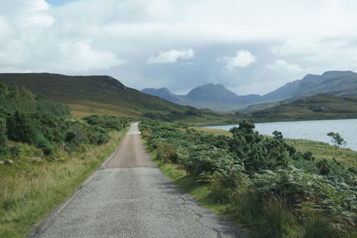 Road leading towards mountains against sky