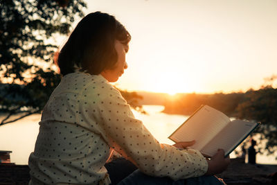 Side view of woman reading book