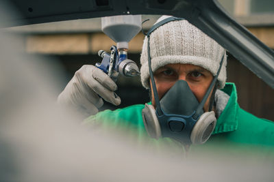 Close-up portrait of man painting while wearing gas mask