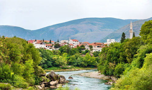 Scenic view of river amidst buildings and mountains against sky