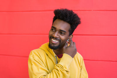 Portrait of smiling young man against red wall