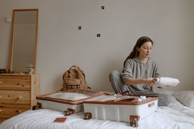 Woman packing clothesbefore going to airport, open suitcase on the bed