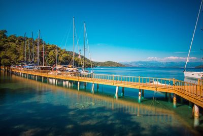 Sailboats moored on sea against clear blue sky