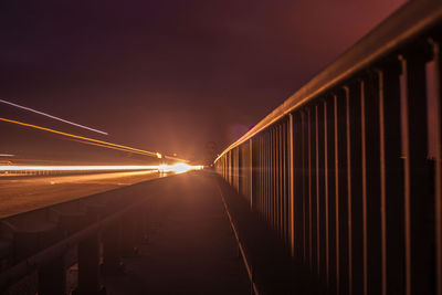 Light trails on bridge against sky at night