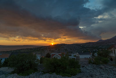 Houses and buildings against sky during sunset