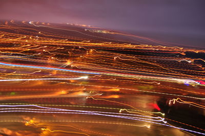 Light trails in city against sky at night