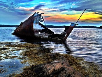 Scenic view of sea against cloudy sky at sunset