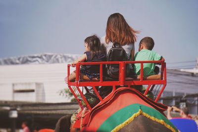 Rear view of people sitting against sky