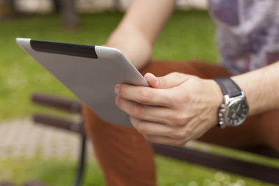 Close-up of man using digital tablet at park