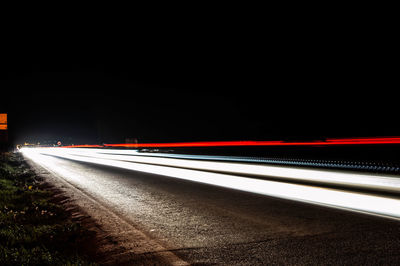 Light trails on road against clear sky at night