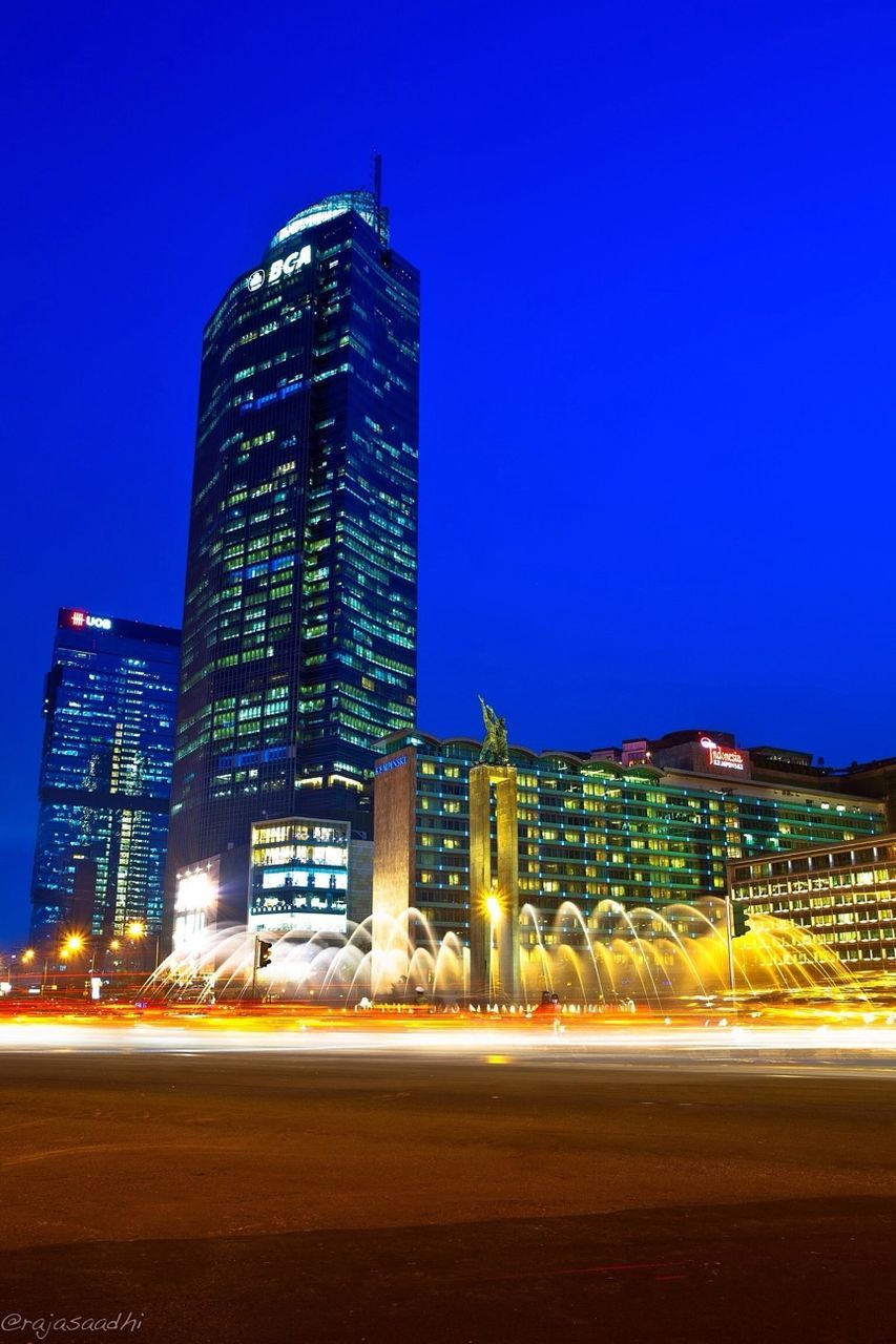 illuminated, building exterior, architecture, built structure, night, clear sky, blue, city, copy space, tower, road, skyscraper, modern, tall - high, street, long exposure, office building, light trail, outdoors, cityscape