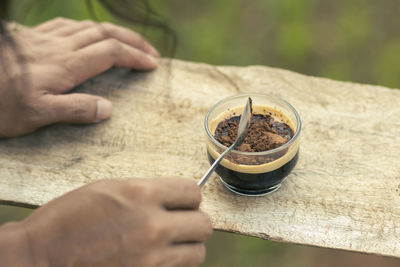 Selective focus cocoa powder in a cup of black coffee in the hand of a man i