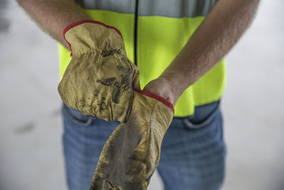 Construction worker putting on protective gloves