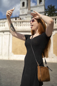 Fashion red hair girl look at phone making funny faces outdoors
