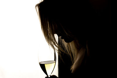 Close-up of woman holding wineglass against white background