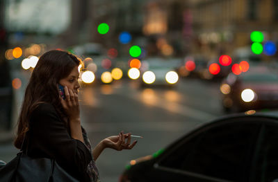 Young woman using mobile phone in city