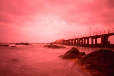 Bridge over sea against cloudy sky