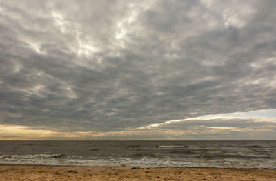 Scenic view of beach against cloudy sky