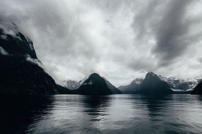 Scenic view of sea by mountains against sky