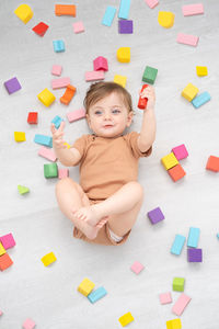 Smiling girl holding toy lying on floor at home