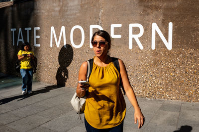 Woman standing by text on wall