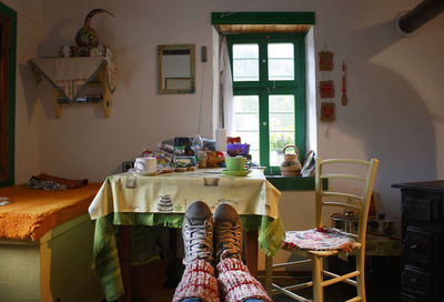 Low section of person against chair and table at home