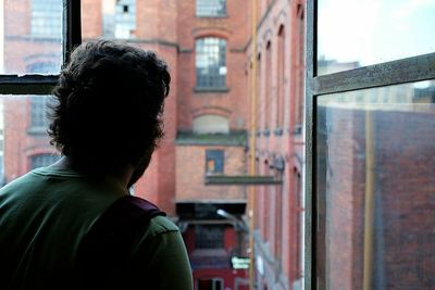 Rear view of woman looking through window