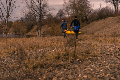 Rear view of men walking on field during winter