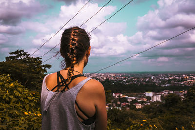 Rear view of man standing by cityscape against sky