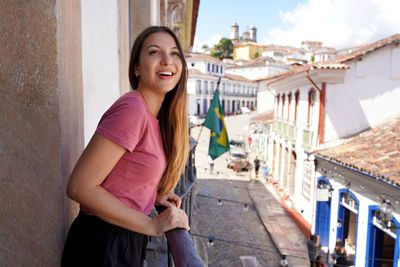 Portrait of young woman standing against buildings