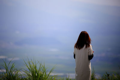 Rear view of woman standing against sky during sunset