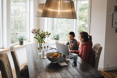 High angle view of mother with autistic son using laptop on table while sitting at home