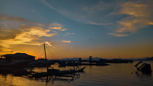 Sailboats moored in marina at sunset