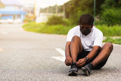 Young man sitting on road