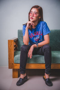 Full length of girl sitting on sofa