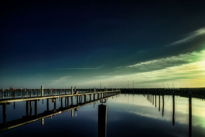 Pier over lake against sky during sunset