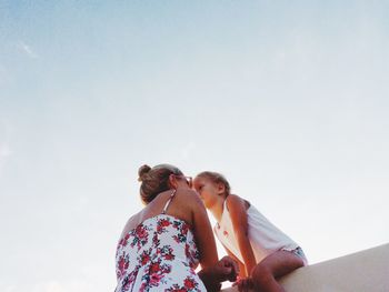 Low angle view of mother and daughter against sky