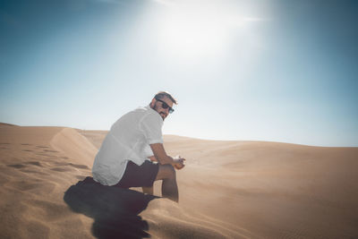 Young man sitting on sand dune in desert