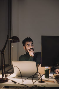 Businessman using computer while working overtime at work place