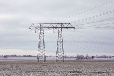 Electricity pylon on field against sky