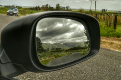 Reflection of clouds in side-view mirror