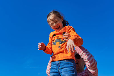 Pretty girl being held up in the air by mom against a blue sky