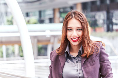 Portrait of smiling young businesswoman standing on elevated walkway 