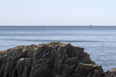 Scenic view of rock on sea against clear sky