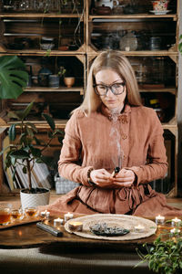 Woman meditating with palo santo in studio, cleaning space with smoke. adult person using burning