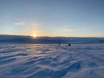 People on snowcapped mountain against sky during sunset